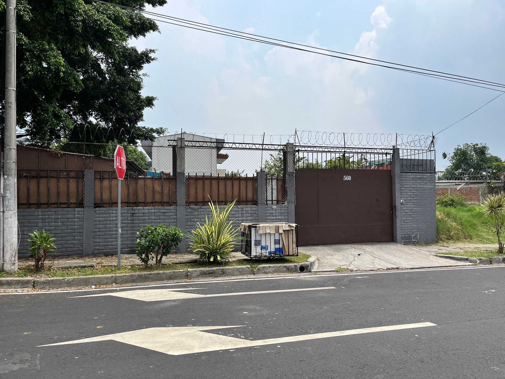 A gated property with a red stop sign, a mailbox, and a small utility shed.