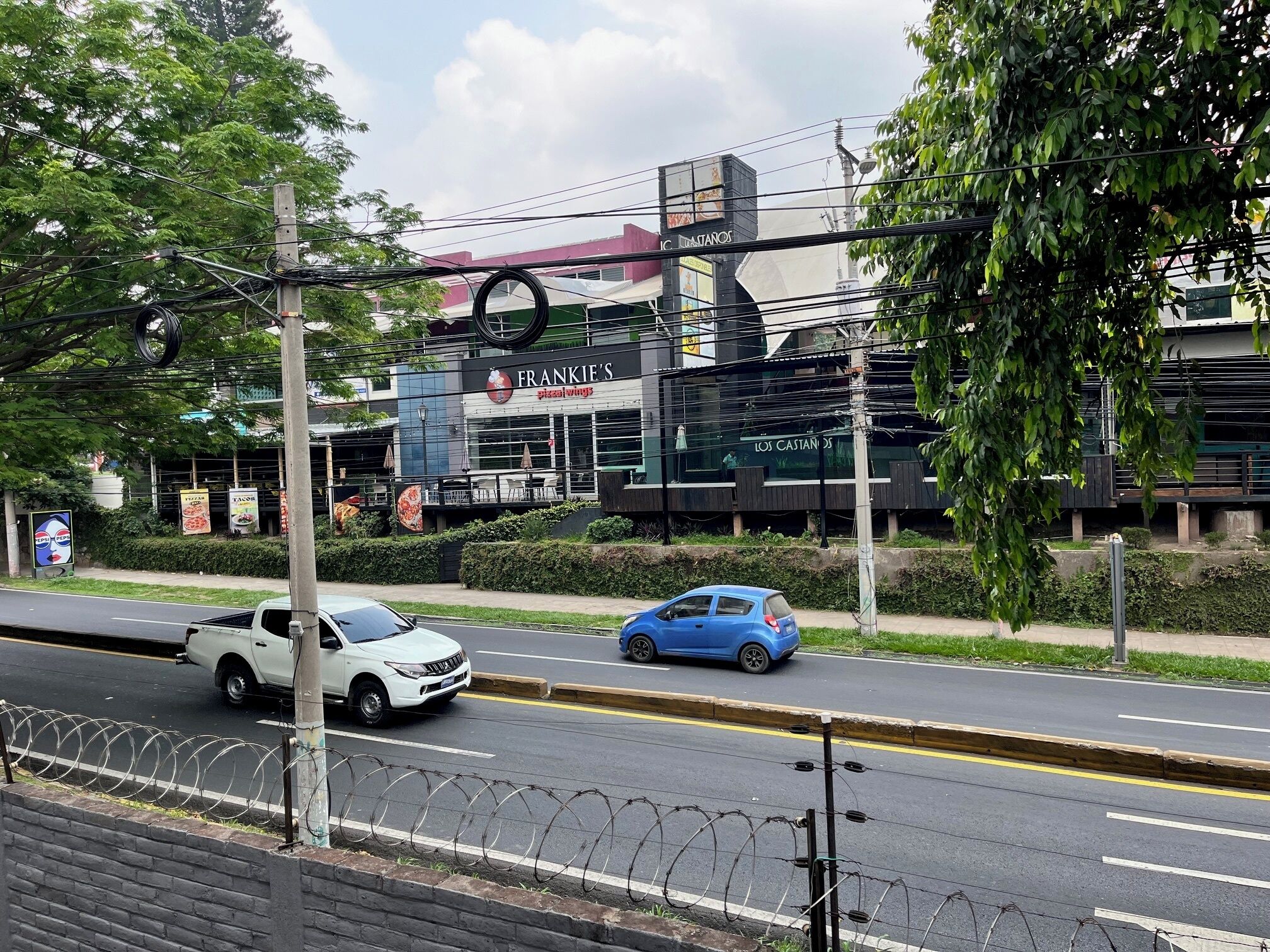 A street view with a restaurant named 'Frankie's Pizza Wings' and 'Los Castanos' across the road.