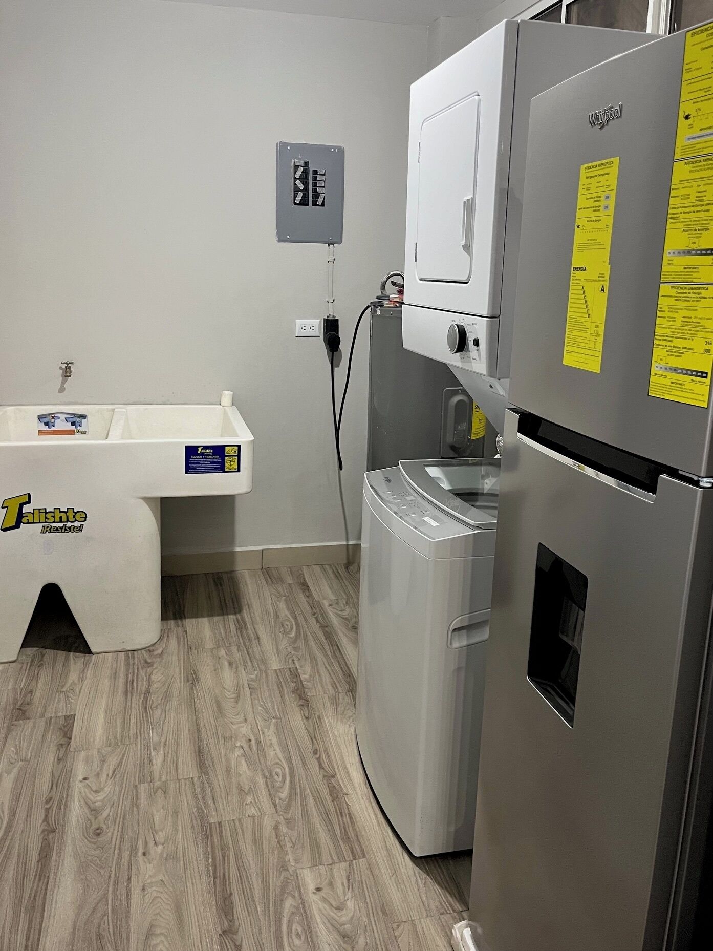 A compact kitchen with a Whirlpool refrigerator, a built-in washer, and a sink with a white countertop.