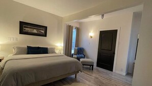 A bedroom with a bed, bedside tables, a chair, a door, and a wall-mounted picture. - 2 bedroom home, Sleeps 6 (Alma)