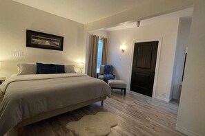 A bedroom with a bed, bedside tables, a chair, a door, and a window with curtains. - 2 bedroom home, Sleeps 6 (Alma)