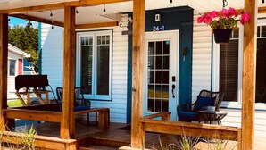A wooden porch with outdoor seating, a grill, and a hanging flower pot. - 2 bedroom home, Sleeps 6 (Alma)