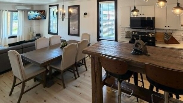 A spacious kitchen with a dining area, wooden flooring, and pendant lighting. - 2 bedroom home, Sleeps 6 (Alma)