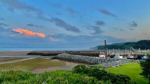 A coastal scene with boats, a rocky breakwater, and a grassy area. - 2 bedroom home, Sleeps 6 (Alma)