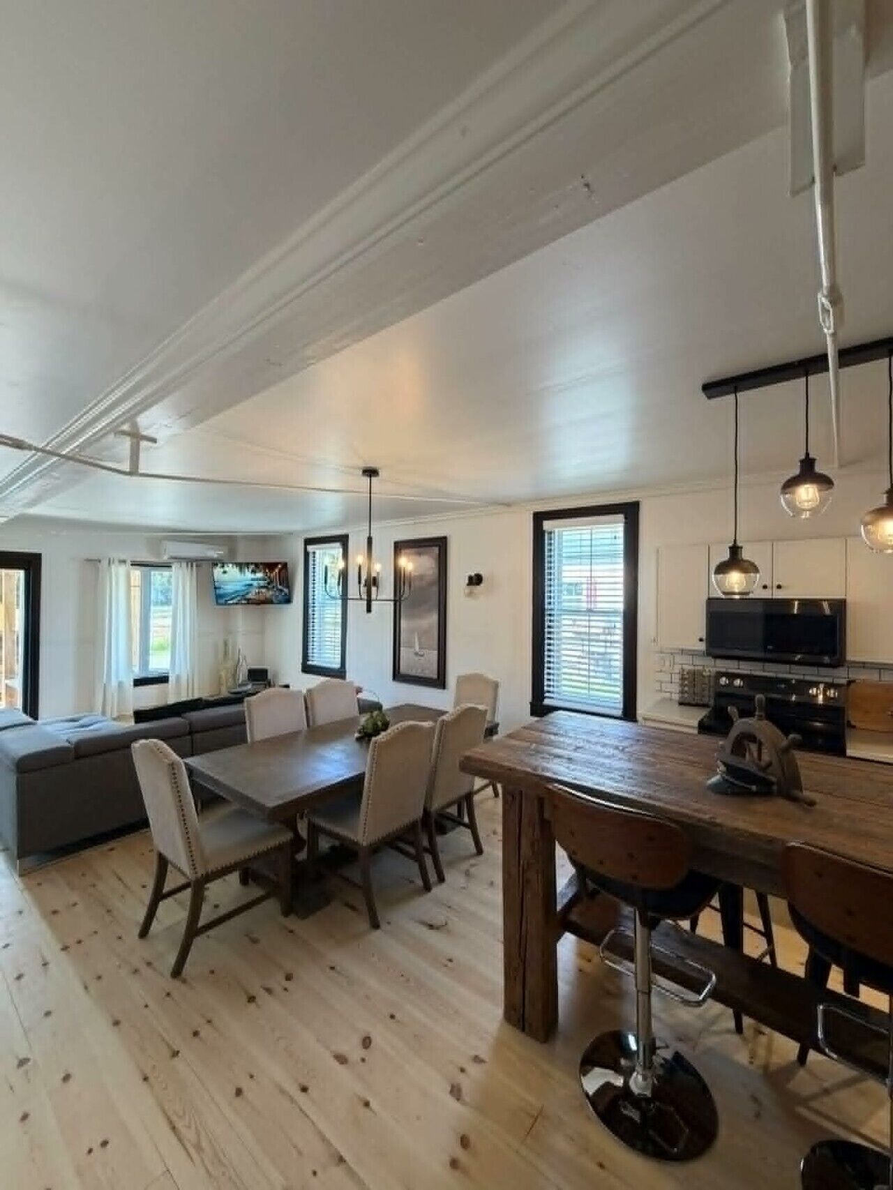 Een moderne keuken met een eethoek, houten vloer en hanglampen.