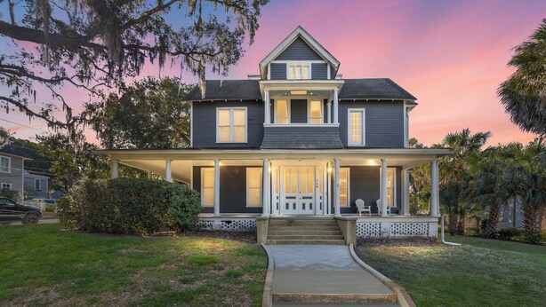 A two-story house with a front porch, a covered entryway, and a driveway leading to the front door. - Victorian Manor: Downtown Apt, near Silver Springs & Fort King Historic Park (Ocala)