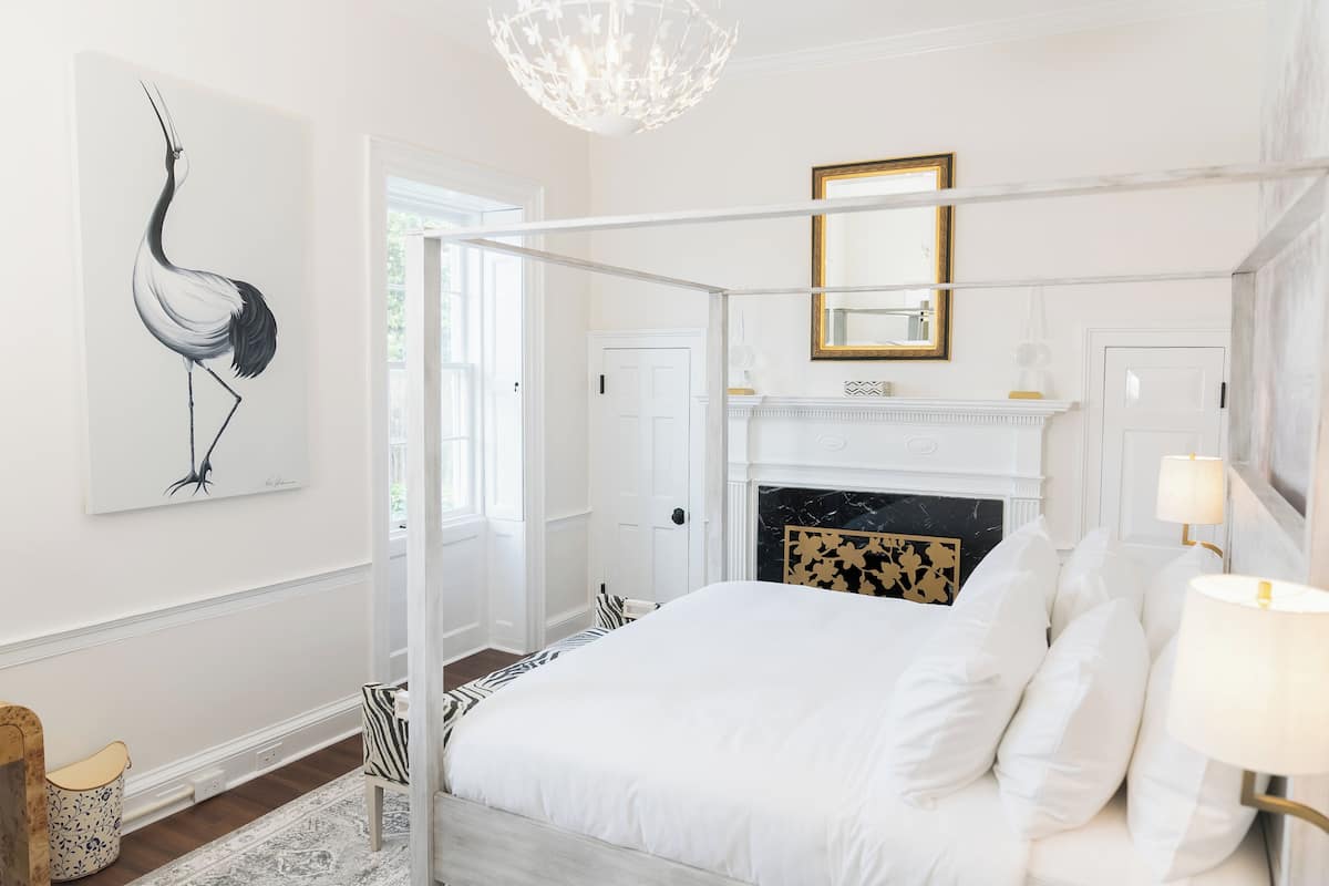 A bedroom with a four-poster bed, a fireplace, and a large mirror.
