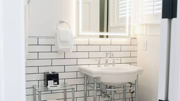 Un baño con lavamanos blanco, un espejo y un perchero para toallas.