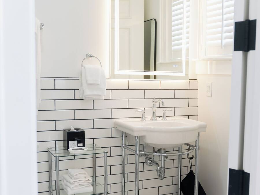 Un baño con lavamanos blanco, un espejo y un perchero para toallas.
