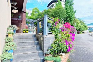 A residential property with a staircase leading to a covered porch, surrounded by potted plants and flowering shrubs. - Deep Breathe Inn (Zixing)