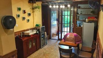 Cocina compacta con comedor, refrigerador y ventana con vista a un jardín.