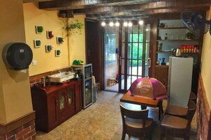 Cocina compacta con comedor, refrigerador y ventana con vista a un jardín.