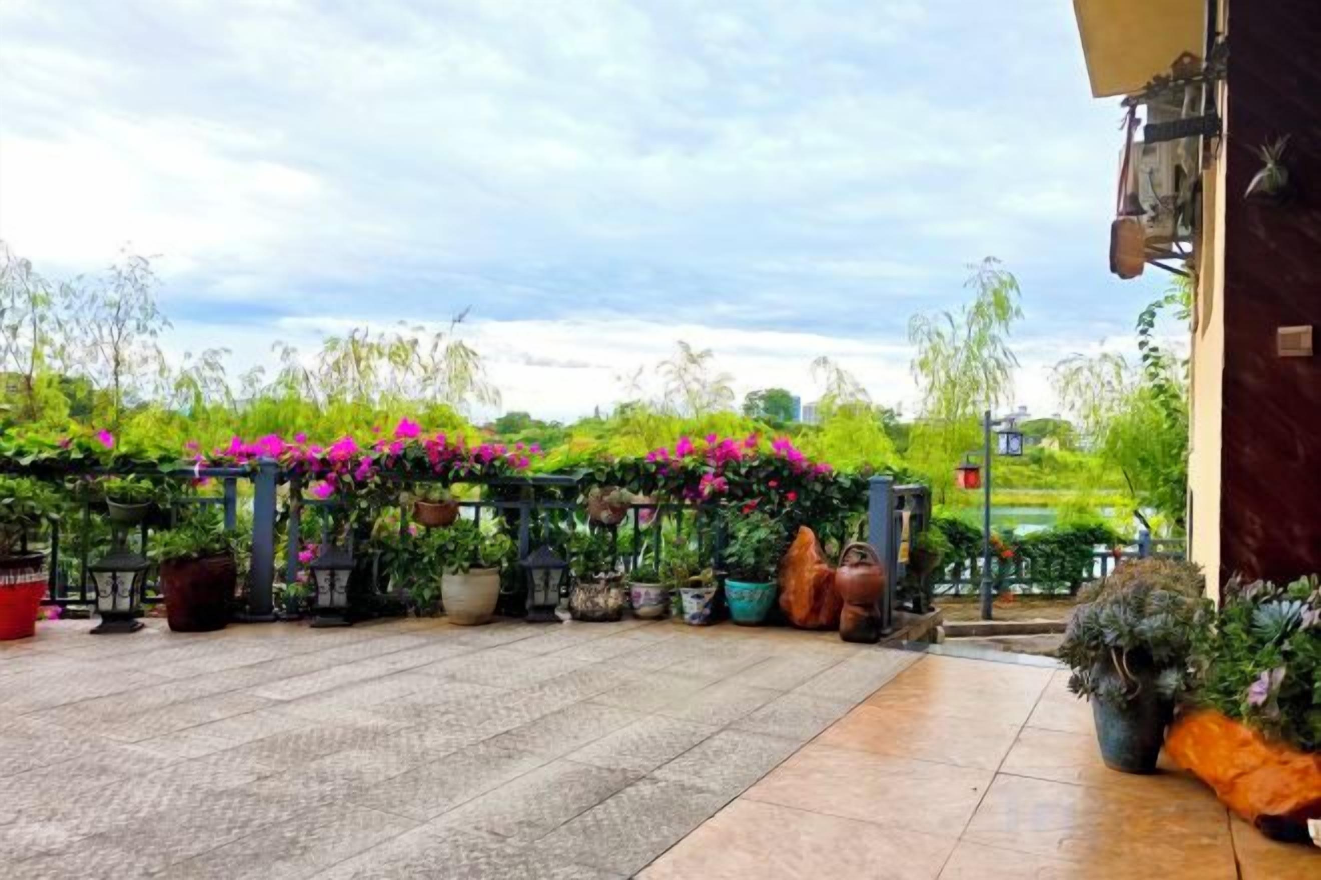 An outdoor patio area with potted plants and a pergola with flowers.