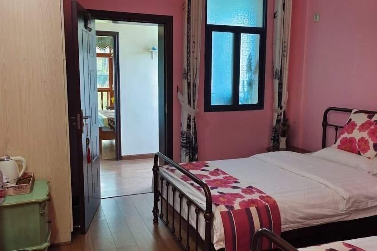 A bedroom with a bed, a green cabinet, a window with curtains, and a door leading to another room.