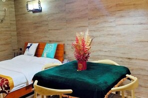 A bedroom with a bed, a nightstand, a chair, and a decorative vase.