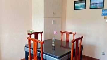 Una mesa de comedor con cuatro sillas, un florero con una flor y dos cuadros en la pared.