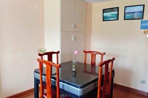 A dining table with four chairs, a vase with a flower, and two framed pictures on the wall.