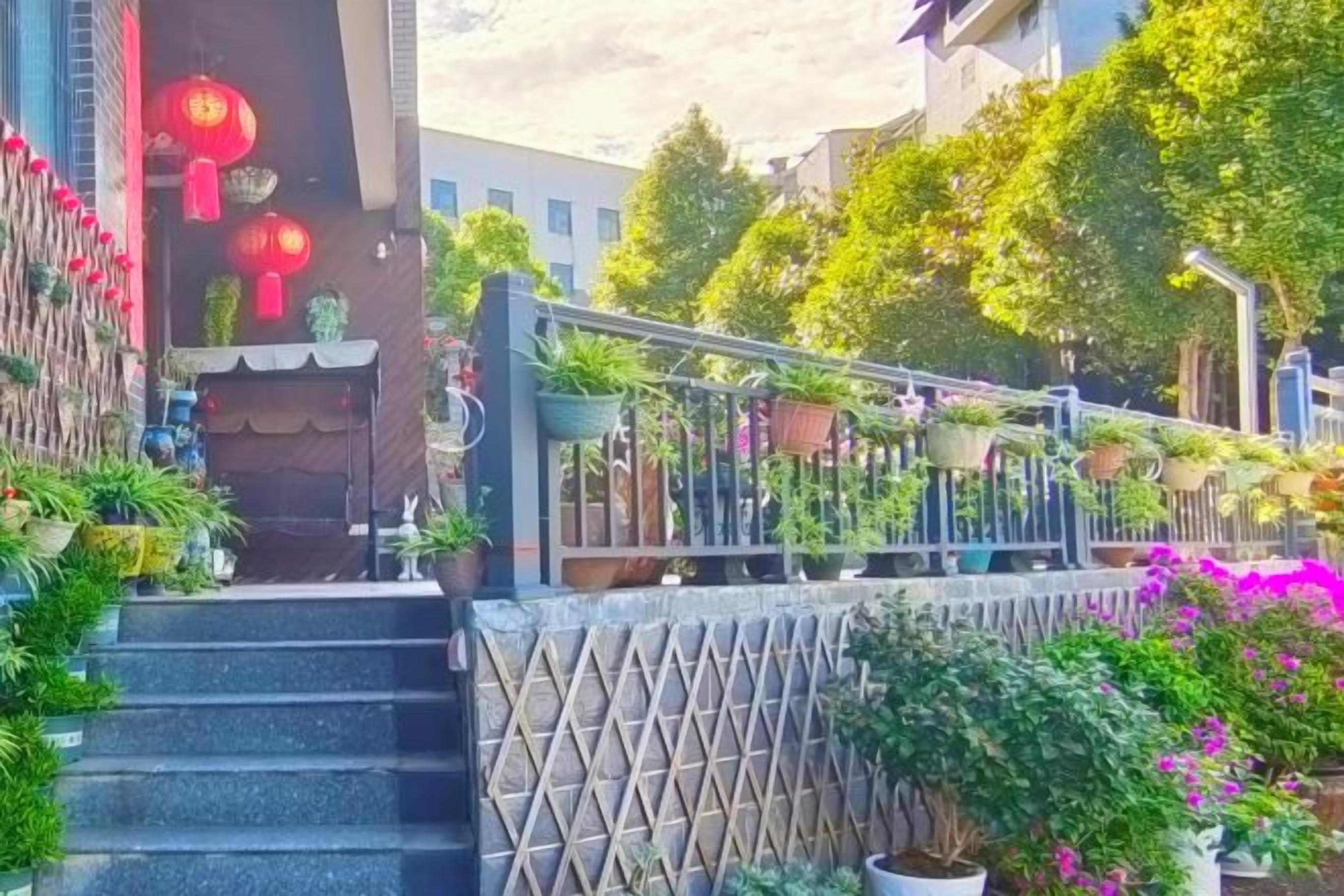 Unes escales condueixen a l'entrada d'un edifici, envoltades de plantes i flors en testos.