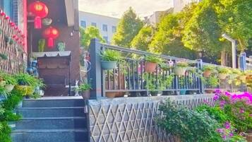 Unes escales condueixen a l'entrada d'un edifici, envoltades de plantes i flors en testos.