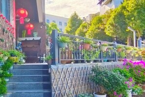 A staircase leading to a building entrance, surrounded by potted plants and flowers. - Deep Breathe Inn (Zixing)