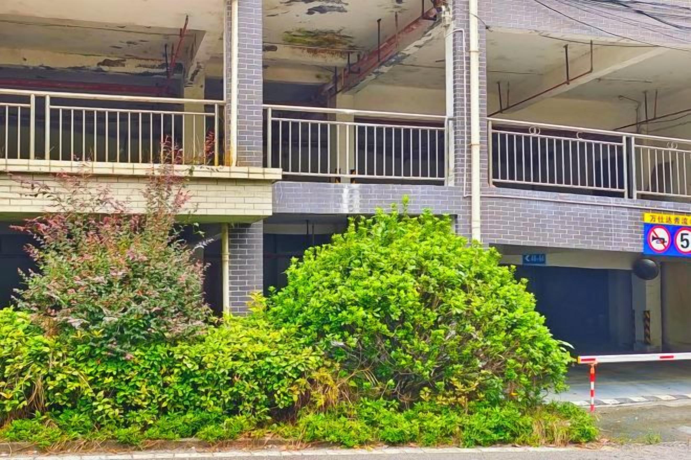A multi-story building with a balcony, a no parking sign, and a gated entrance.