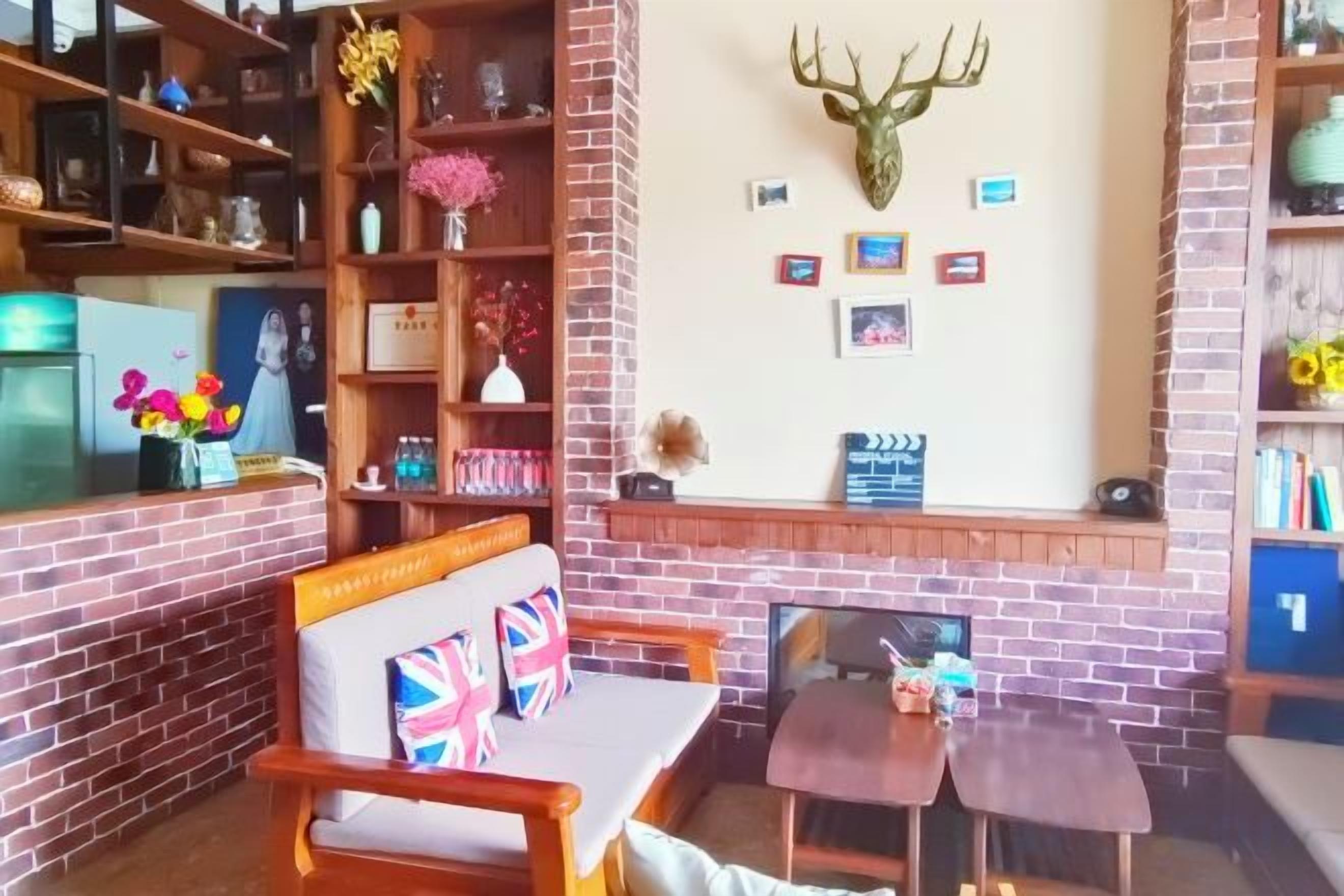 A cozy interior with a brick fireplace, wooden furniture, and a deer head mounted on the wall.