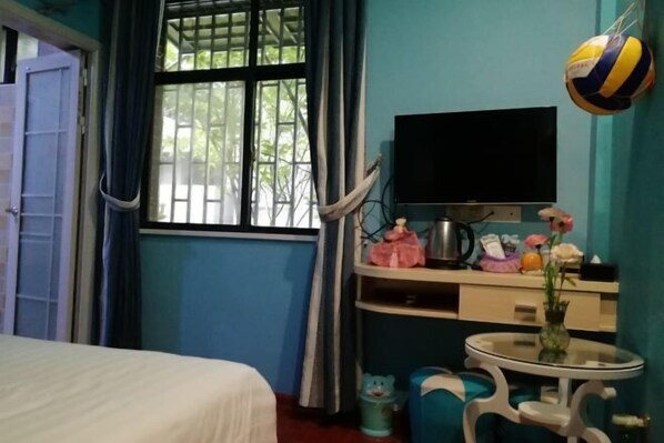 A room with a bed, a TV, a small table with a vase, and a window with curtains. - Deep Breathe Inn (Zixing)