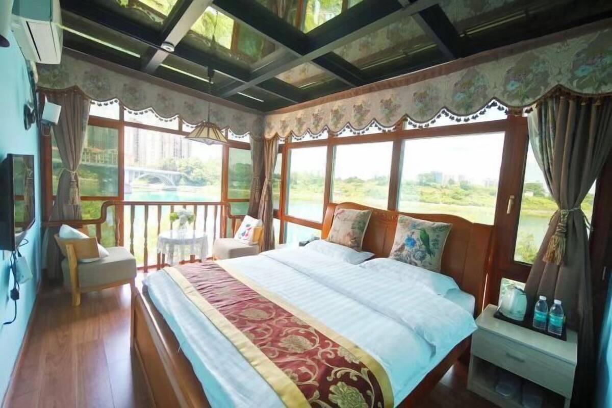 Une chambre avec un grand lit, une petite table, une chaise et une fenêtre donnant sur un paysage verdoyant.