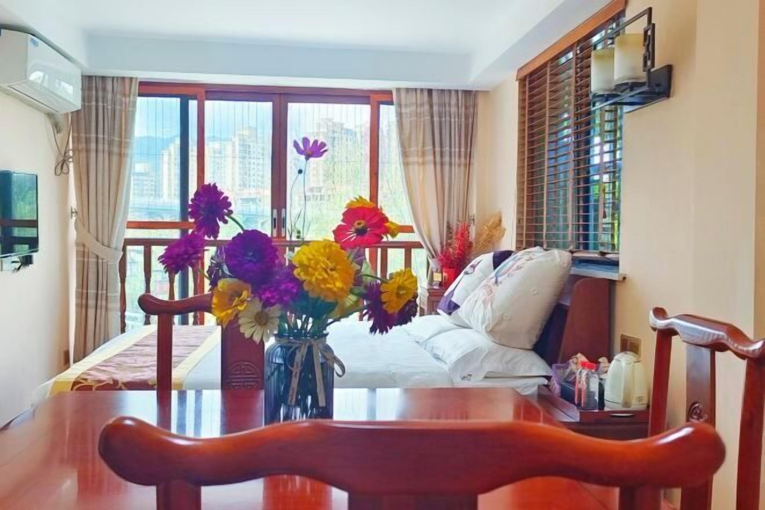 Una habitación de hotel con una mesa de comedor, sillas, un sofá y un ventanal con cortinas.