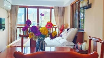 Una habitación de hotel con una mesa de comedor, sillas, un sofá y un ventanal con cortinas.