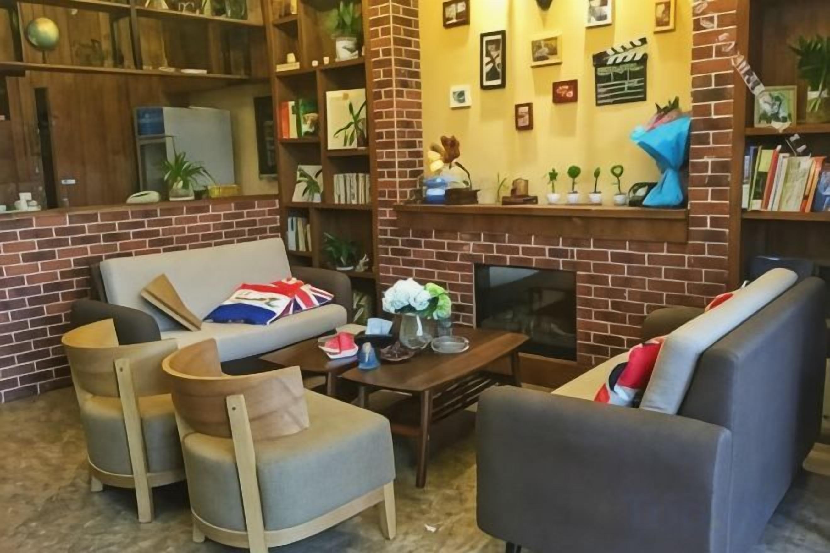 Una sala de estar acogedora con chimenea de ladrillo, un sofá y una estantería llena de libros y objetos decorativos.