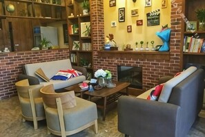 A cozy living room with a brick fireplace, a sofa, and a bookshelf filled with books and decorative items. - Deep Breathe Inn (Zixing)