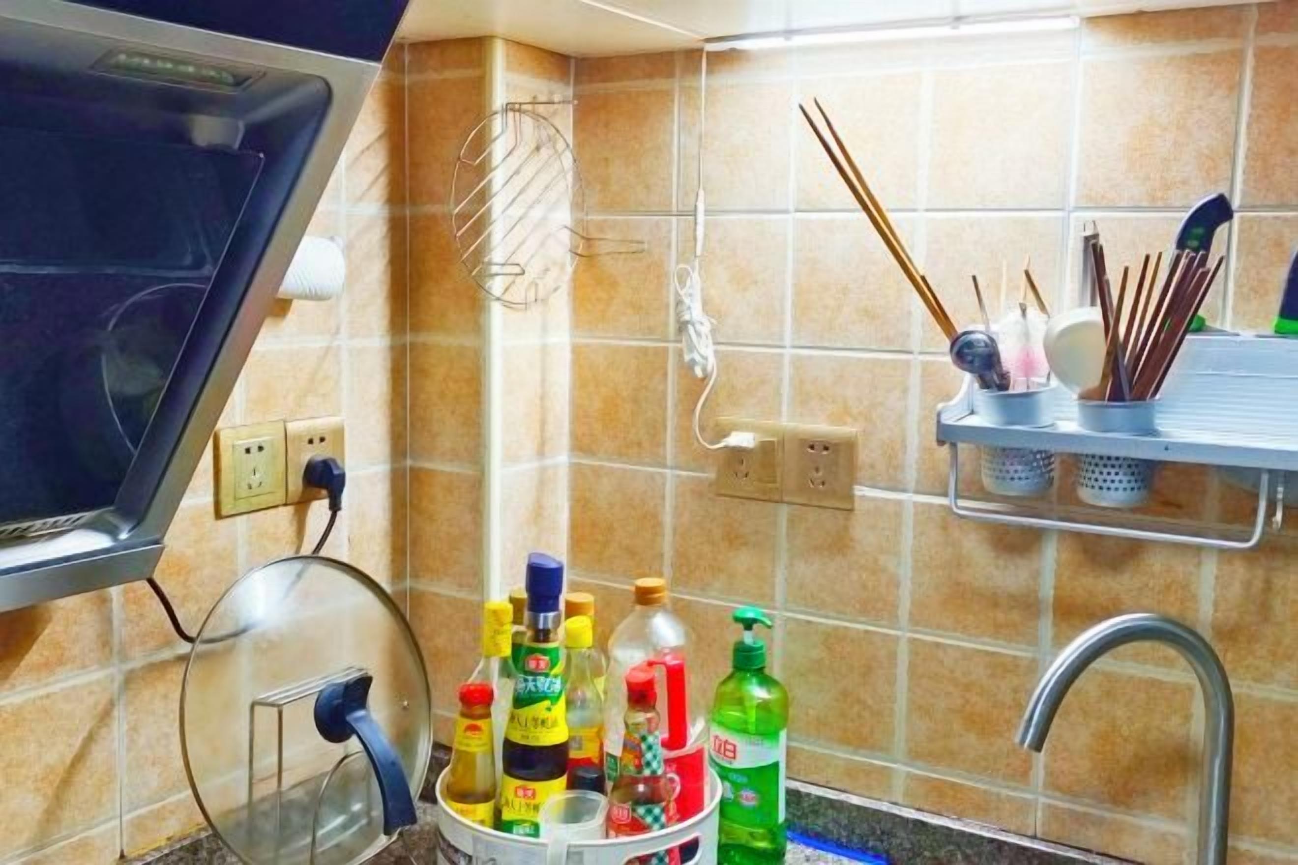 A kitchen with a microwave, a kettle, and various condiments on a shelf.