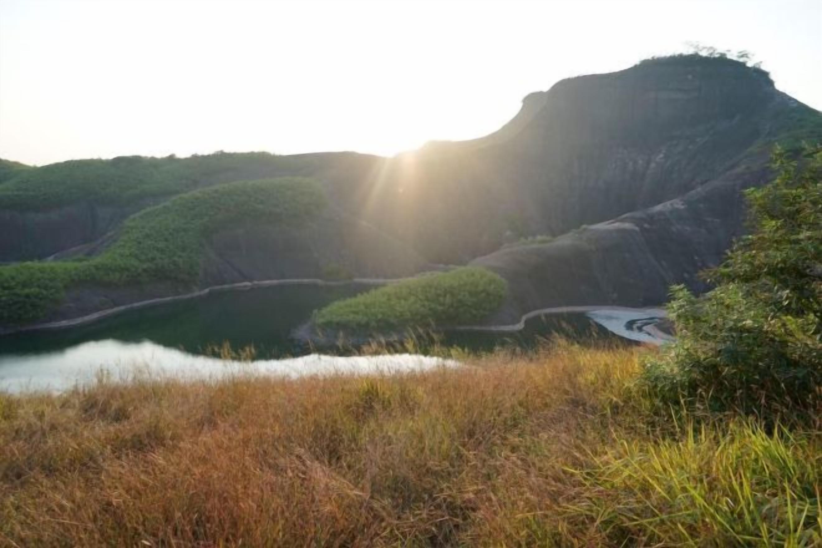 A natural landscape with a body of water, a hill, and a road.