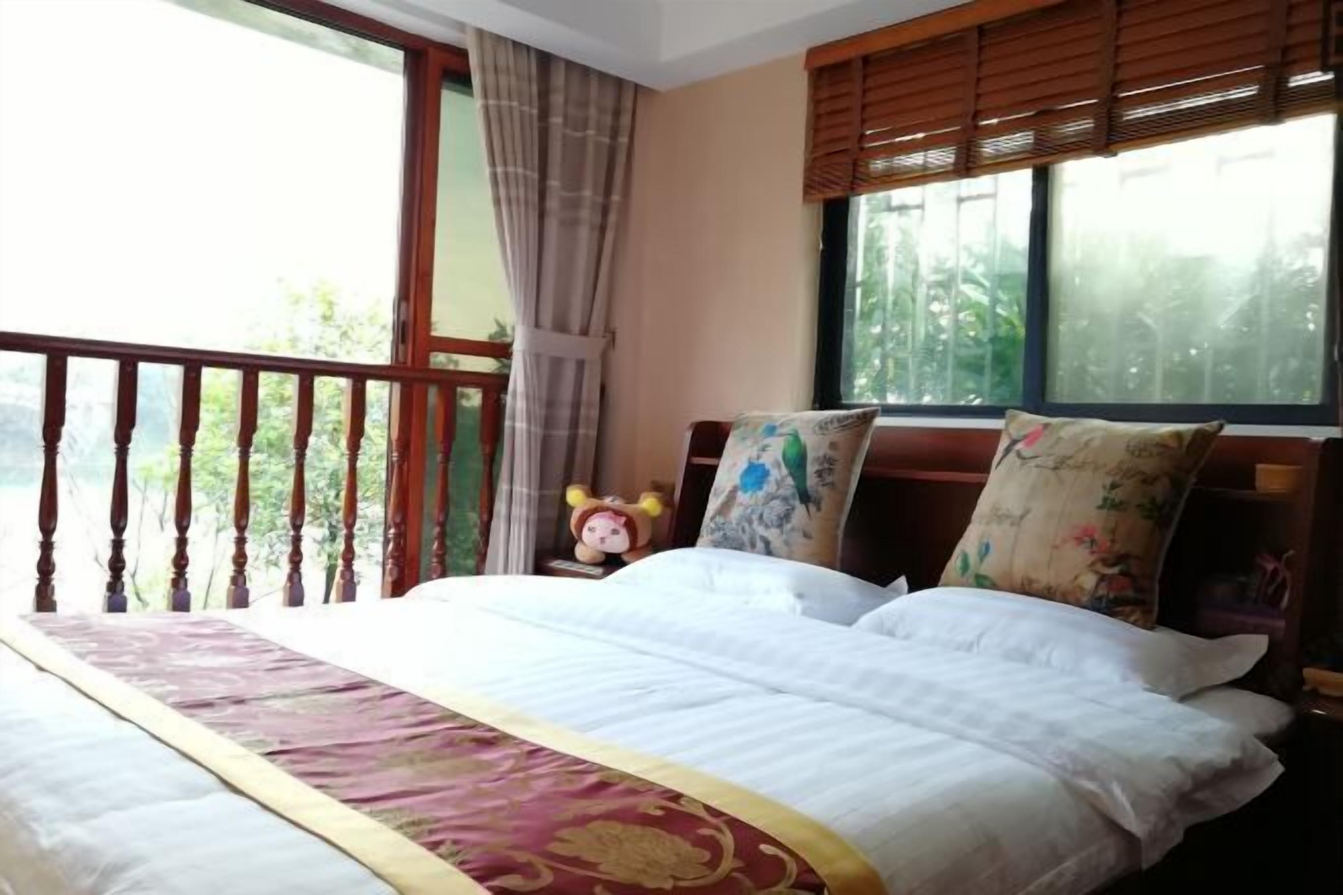 A bedroom with a bed, a balcony, and a window with blinds.