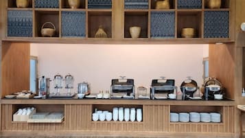 Una estación de café con mostrador de madera, estantes con cestas y diversos equipos para preparar café.
