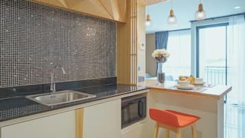 Una cucina moderna con rivestimento a mosaico nero, lavello in acciaio inossidabile e forno a microonde. C'è un'isola in legno con una sedia rossa e un vaso di fiori.
