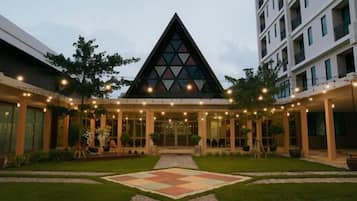 A hotel with a central atrium, a triangular glass structure, and a courtyard with a geometric patterned area.