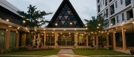 A hotel with a central atrium, a triangular glass structure, and a courtyard with a geometric patterned area.