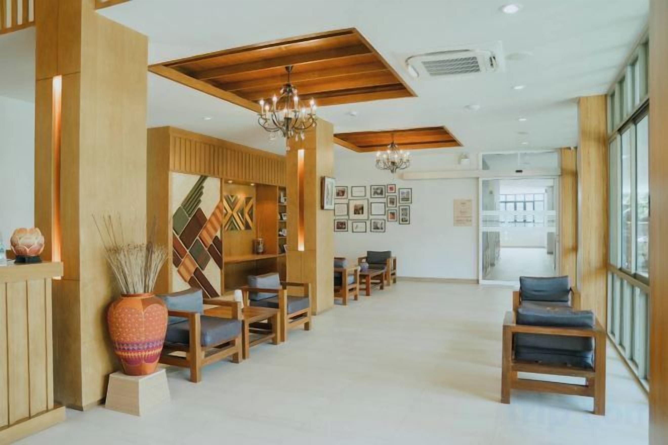 Vestíbulo de hotel con mobiliario de madera, un mostrador de recepción y una araña.