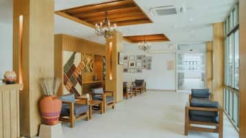 Vestíbulo de hotel con mobiliario de madera, un mostrador de recepción y una araña.