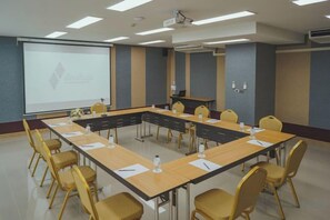 A conference room with a long table, chairs, a projector screen, and a presentation on the wall. - The Cotton Tree Hometel (Khon Kaen)