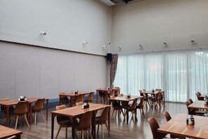 A conference room with multiple tables and chairs, a high ceiling, and large windows with curtains. - The Cotton Tree Hometel (Khon Kaen)