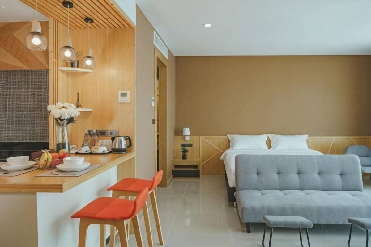 Ein modernes Hotelzimmer mit Küchenzeile, einem Bett, einer Couch und einem Essbereich.