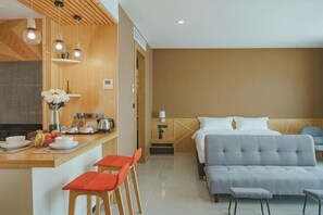 A modern hotel room with a kitchenette, a bed, a sofa, and a dining area. - The Cotton Tree Hometel (Khon Kaen)
