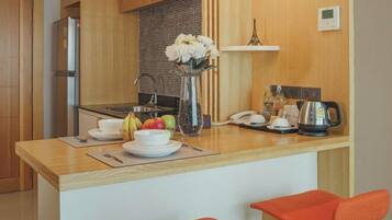 A compact kitchen with a wooden countertop, a refrigerator, a sink, and a small dining area with two red chairs.