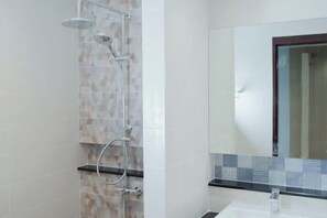 Un baño con ducha, lavamanos y espejo.
