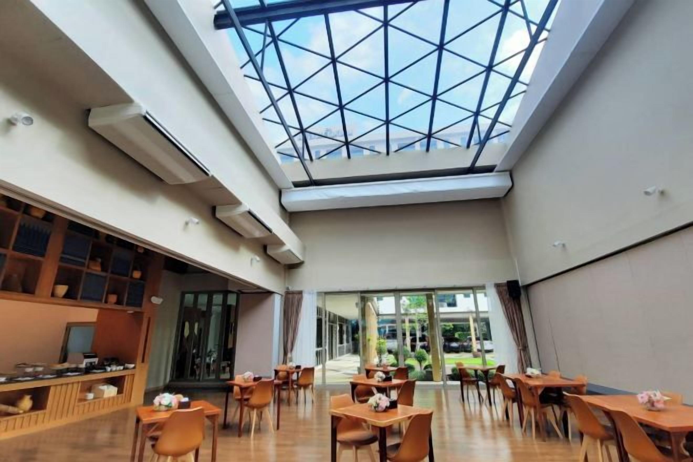 A spacious indoor area with a high ceiling and a skylight, featuring tables and chairs arranged for dining.