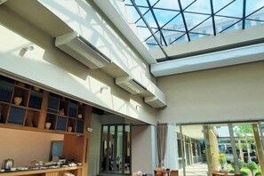 A spacious interior with a high ceiling, skylights, and a view of the outdoors. - The Cotton Tree Hometel (Khon Kaen)