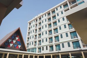 A multi-story hotel with balconies and a distinctive geometric building in the foreground. - The Cotton Tree Hometel (Khon Kaen)